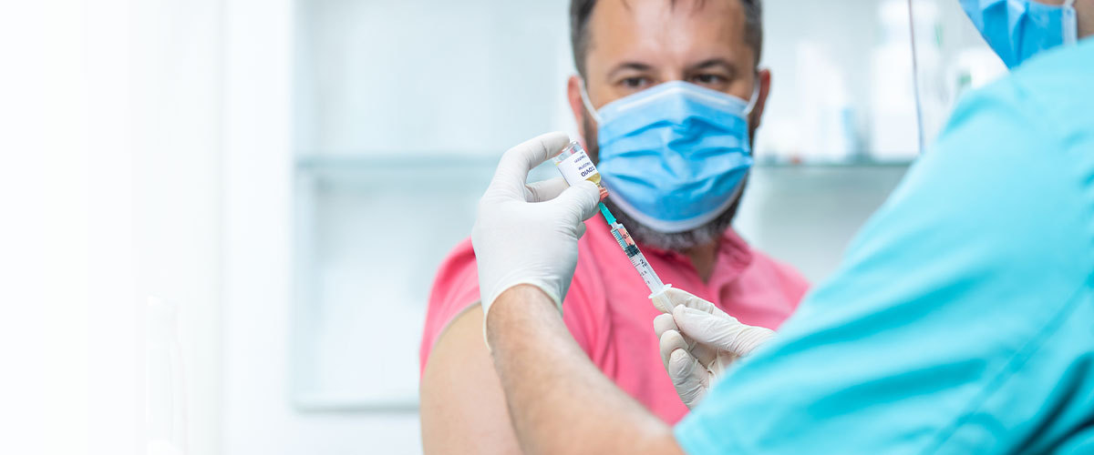 Man wearing a mask and receiving vaccine.