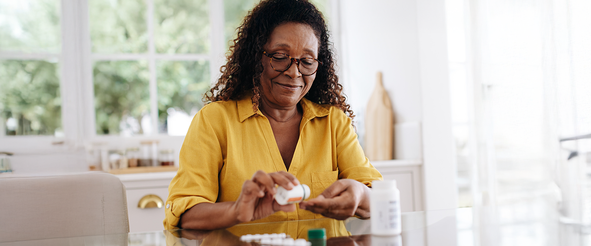 Woman removing medication from a prescription pill bottle.