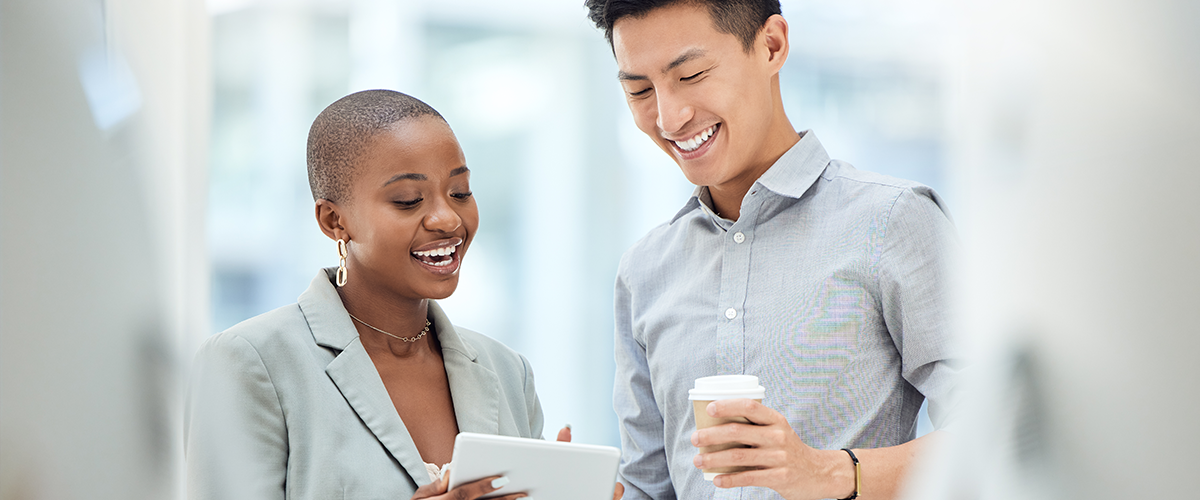 Two people smiling and talking in an office setting.