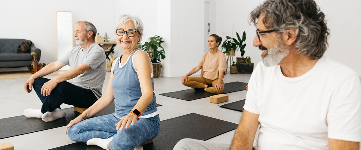 A group of older men and women participating in a yoga class.